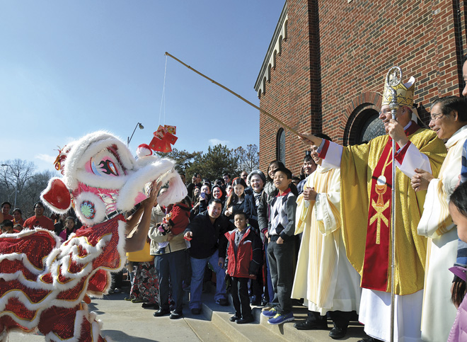 The youth of the Church of the Holy Martyrs brought out a brand new dragon for Bishop Robert W. Finn to feed at the end of the parish’s annual Mass Feb. 21 celebrating the Oriental lunar new year of Tet. (Kevin Kelly/Key photo)