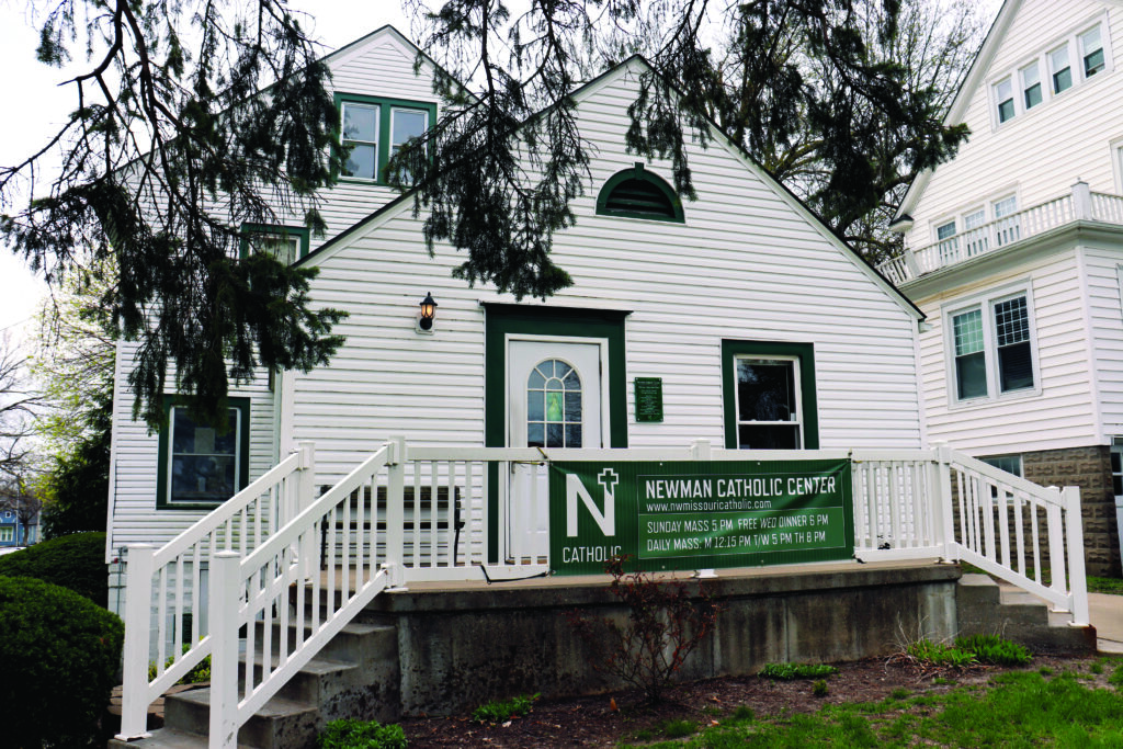 Northwest Missouri State University Newman Center; a white house with green trim and a porch, with a Newman Center banner on the porch railing.